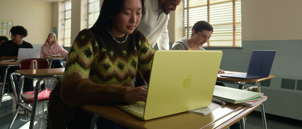 Estudante usando o MacBook Neo na cor amarelo-cítrico desconectado da tomada em uma sala de aula