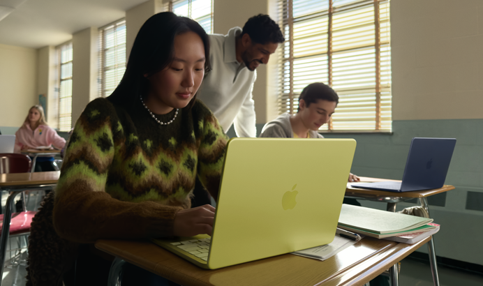 Estudante usando o MacBook Neo na cor amarelo-cítrico desconectado da tomada em uma sala de aula