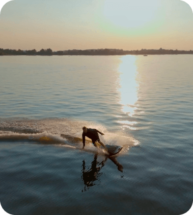 Imagem de um surfistando em sua prancha no mar em um final de tarde