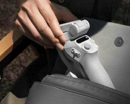 Imagem da mão de uma pessoa armazenando o DJI Osmo Mobile SE em uma bolsa, demonstrando seu comportamento dobrável