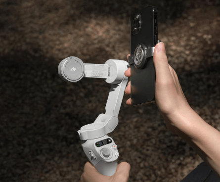 Imagem de uma pessoa acoplando um celular no DJI Osmo Mobile SE, demonstrando seus recursos de estabilizador e suporte magnético