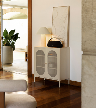Sala de estar ampla com piso de madeira, sofá de couro e janelas grandes para o jardim.